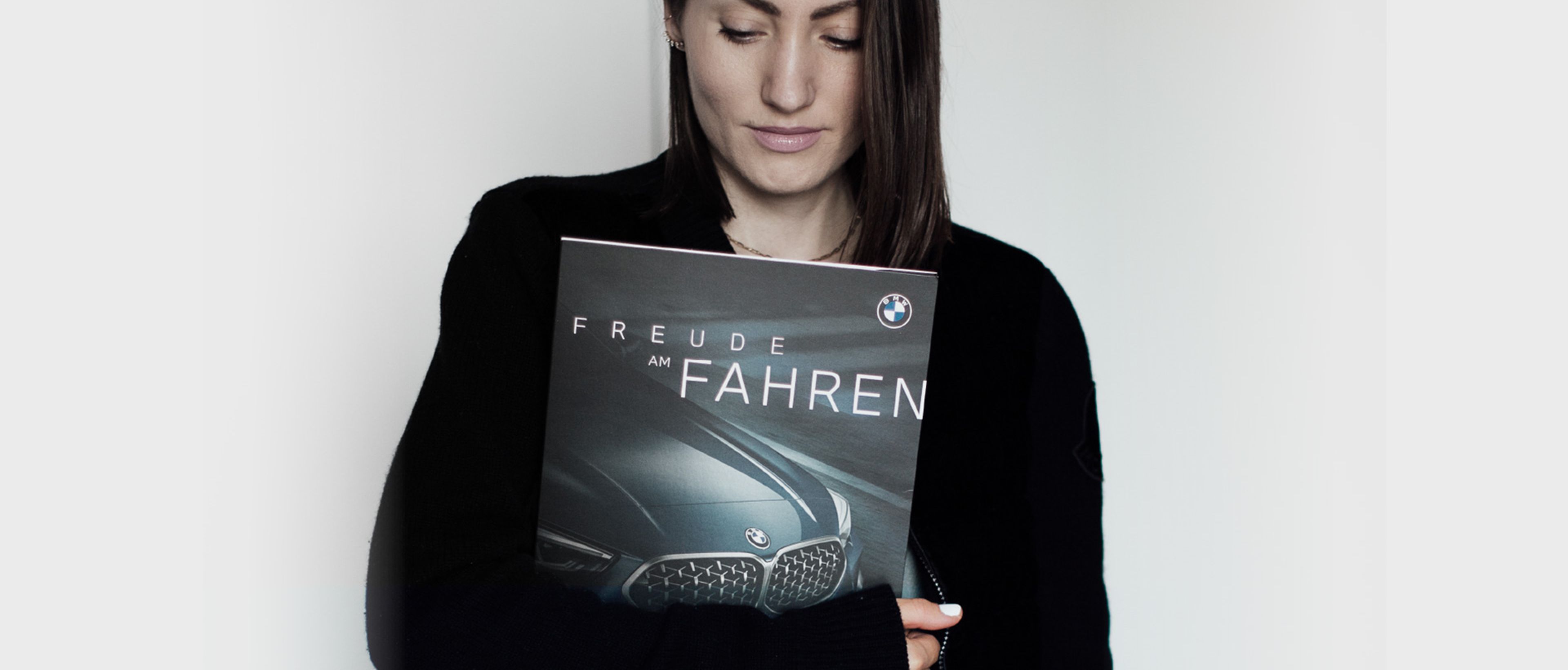 Frau hält Angebotsmappe von BMW mit Aufschrift "Freude am Fahren"