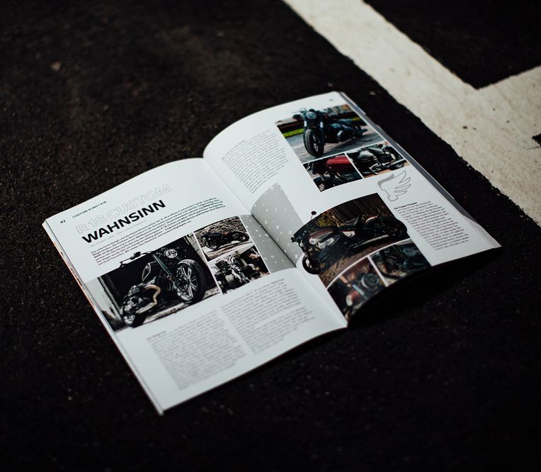 Geöffnetes BMW Motorrad Magazin 2022 auf schwarzem Asphalt liegend