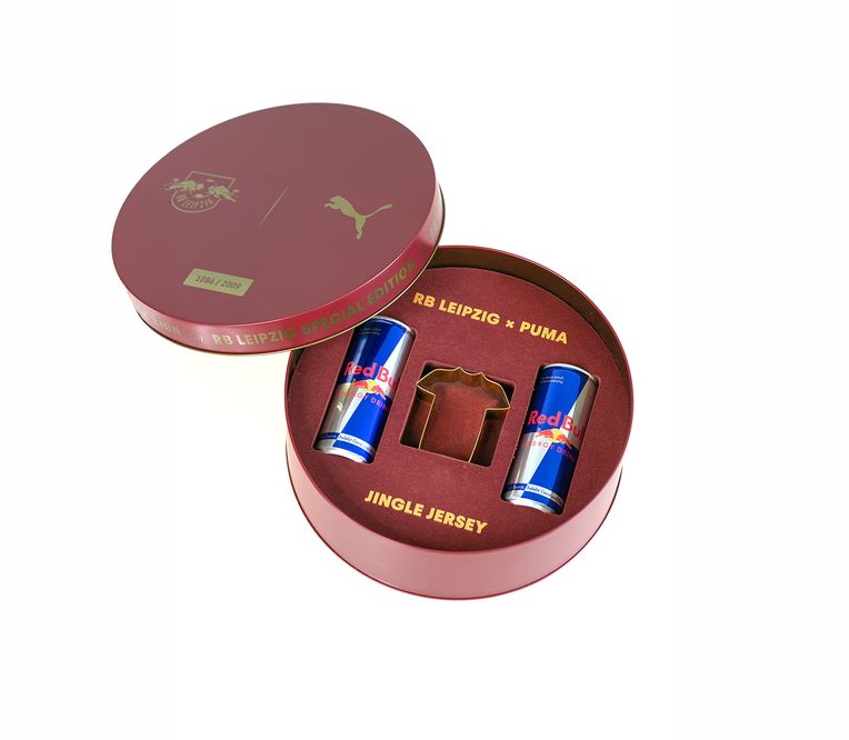 RB Leipzig Sonderedition-Set mit zwei Red Bull-Dosen und einem Trikotausschnitt, verpackt in einer rundlichen, kastanienbraunen Box der Marke Puma.