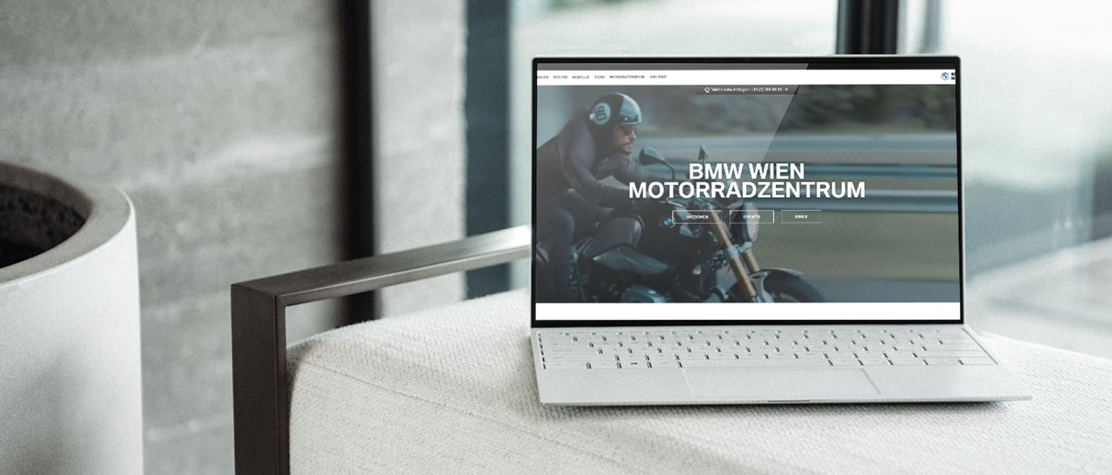 Laptop auf Couch mit offener Webseite des BMW Wien Motorradzentrums
